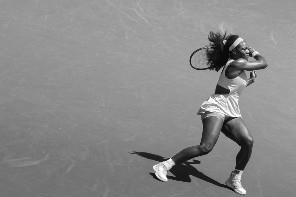 A black and white image of Serena Williams swinging a racket during a match