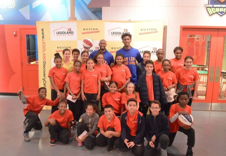 Two Harlem Globetrotter posing with a group of children