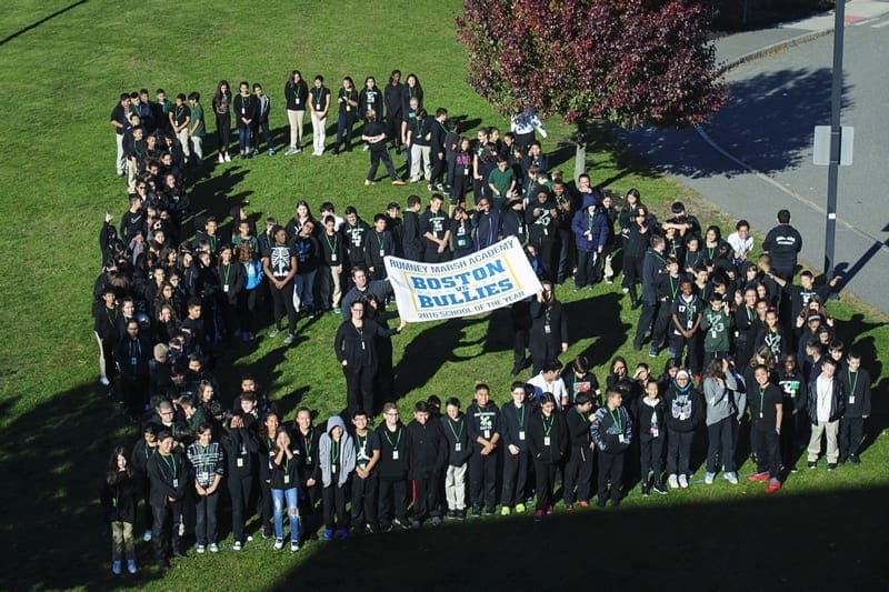 a group of students standing on grass holding a banner