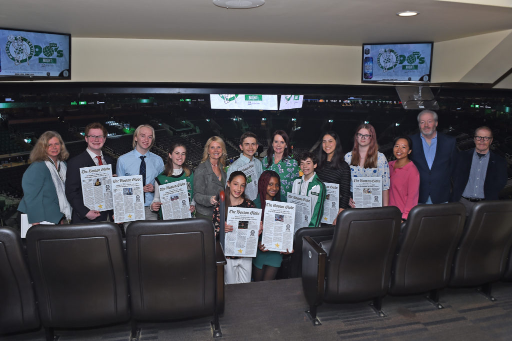 A group of people from the Will McDonough Writing Contest holding their essays in front of the TD Garden Arena.